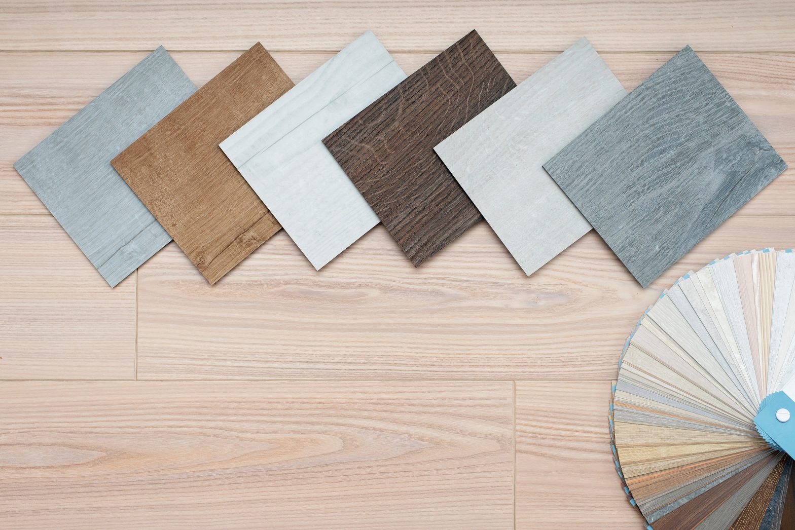 An example of a catalog of luxury vinyl floor tiles and a designer palette with textures with a new interior design for a house or floor on a light wooden background.